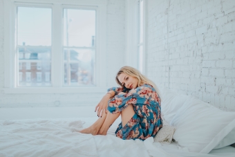 woman-wearing-floral-dress-while-sitting-on-bed-3586911